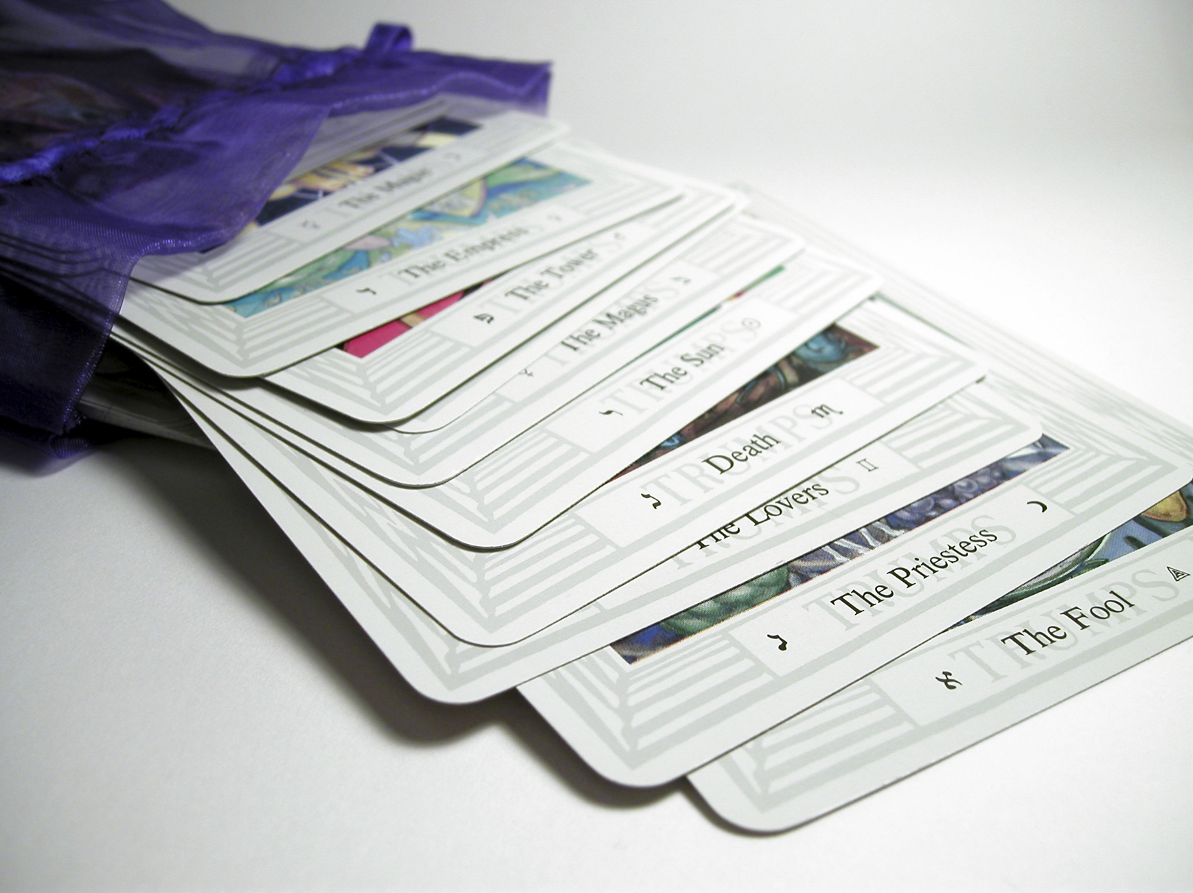 A deck of tarot cards spilling out of a purple cloth case on a white table